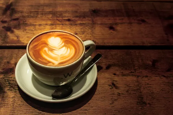 Latte art dans une tasse en céramique sur du bois ensoleillé
